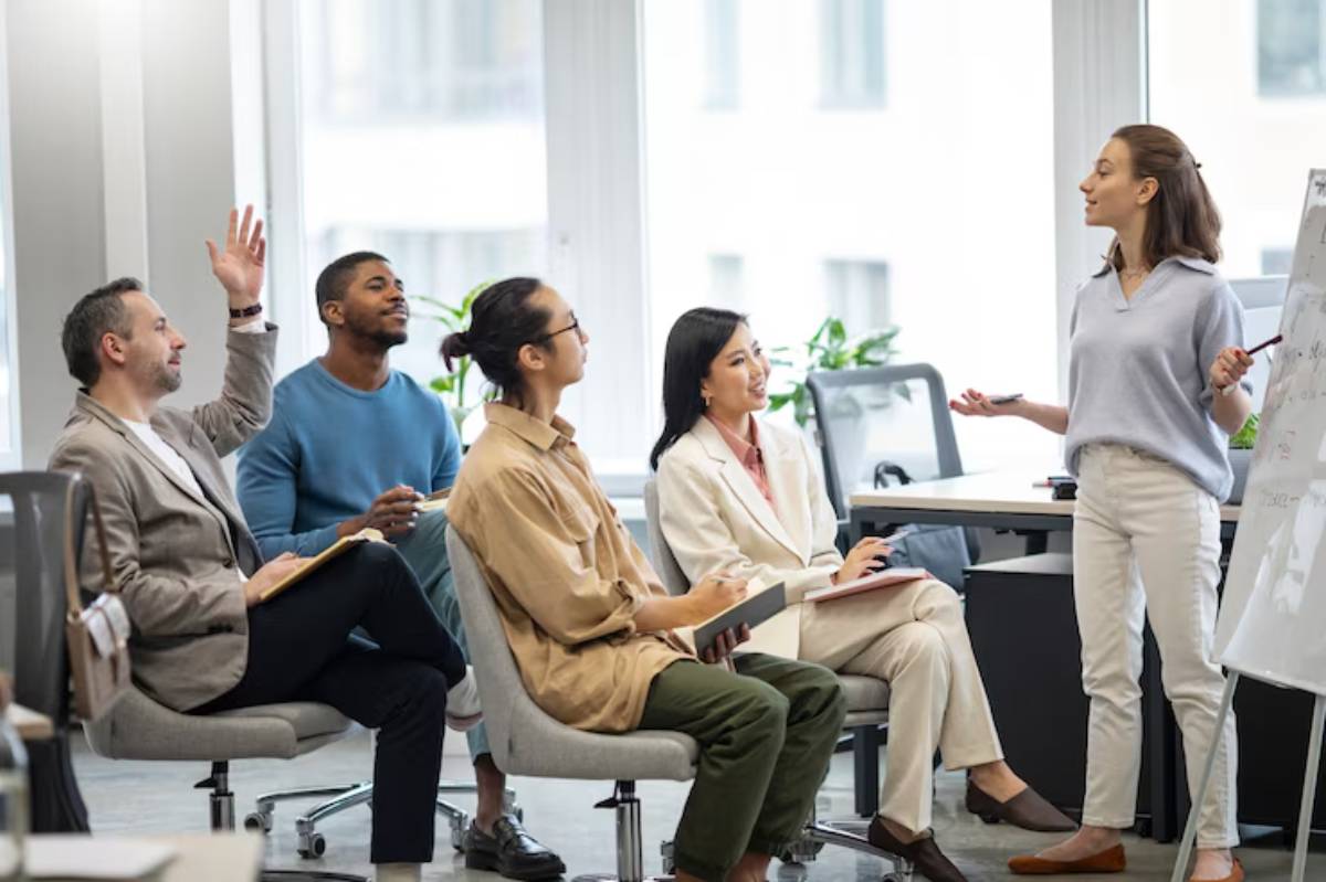 A group of professionals engaged in a meeting, with one person presenting ideas at a whiteboard while others listen attentively.