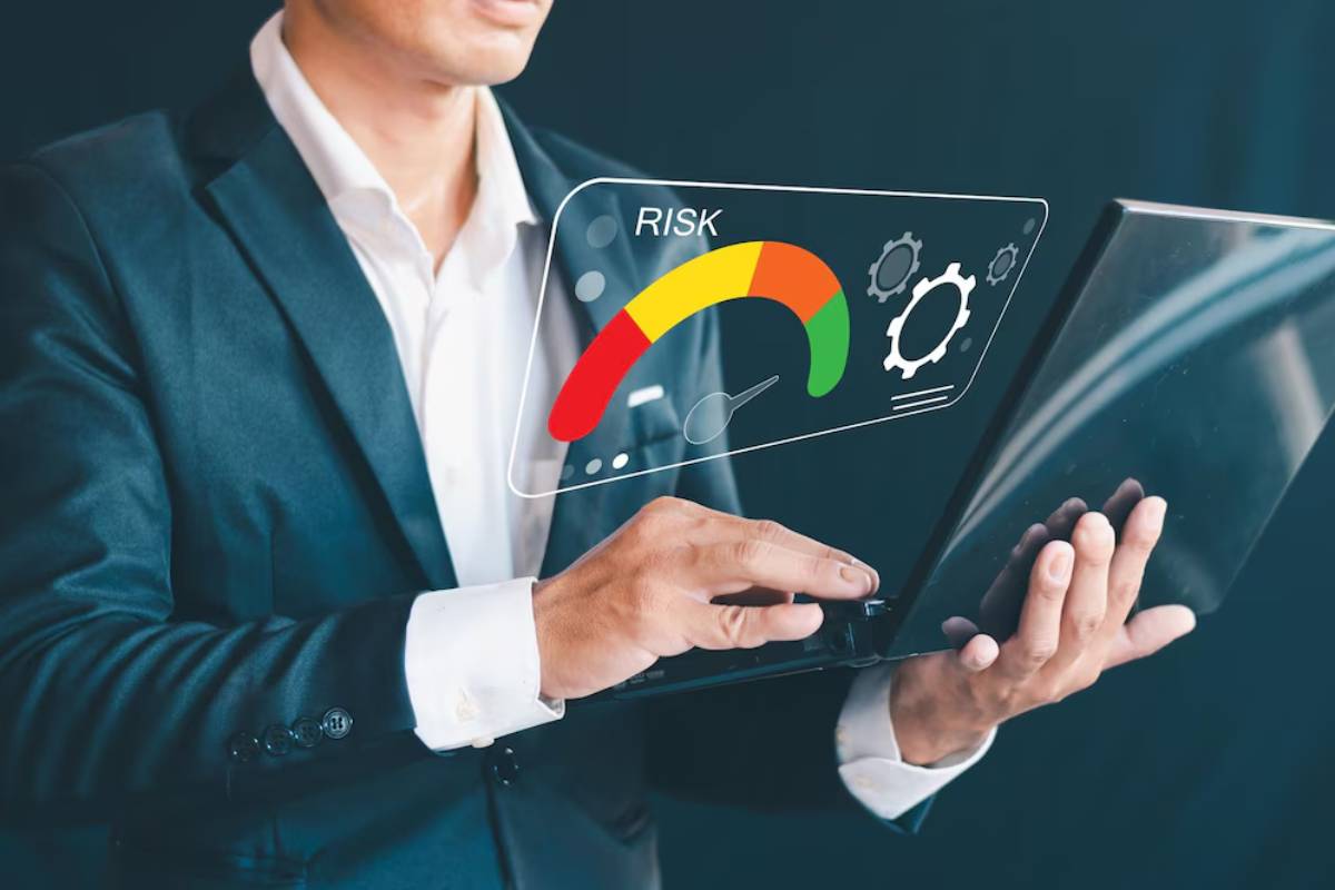 A businessman in a suit interacts with a laptop displaying a risk assessment gauge, highlighting risk levels with colors.