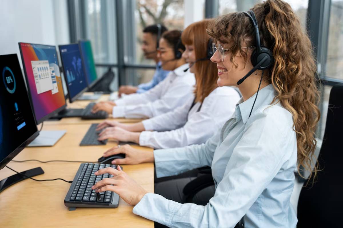 A group of professionals wearing headsets work at computers, focusing on screens in a modern office environment.
