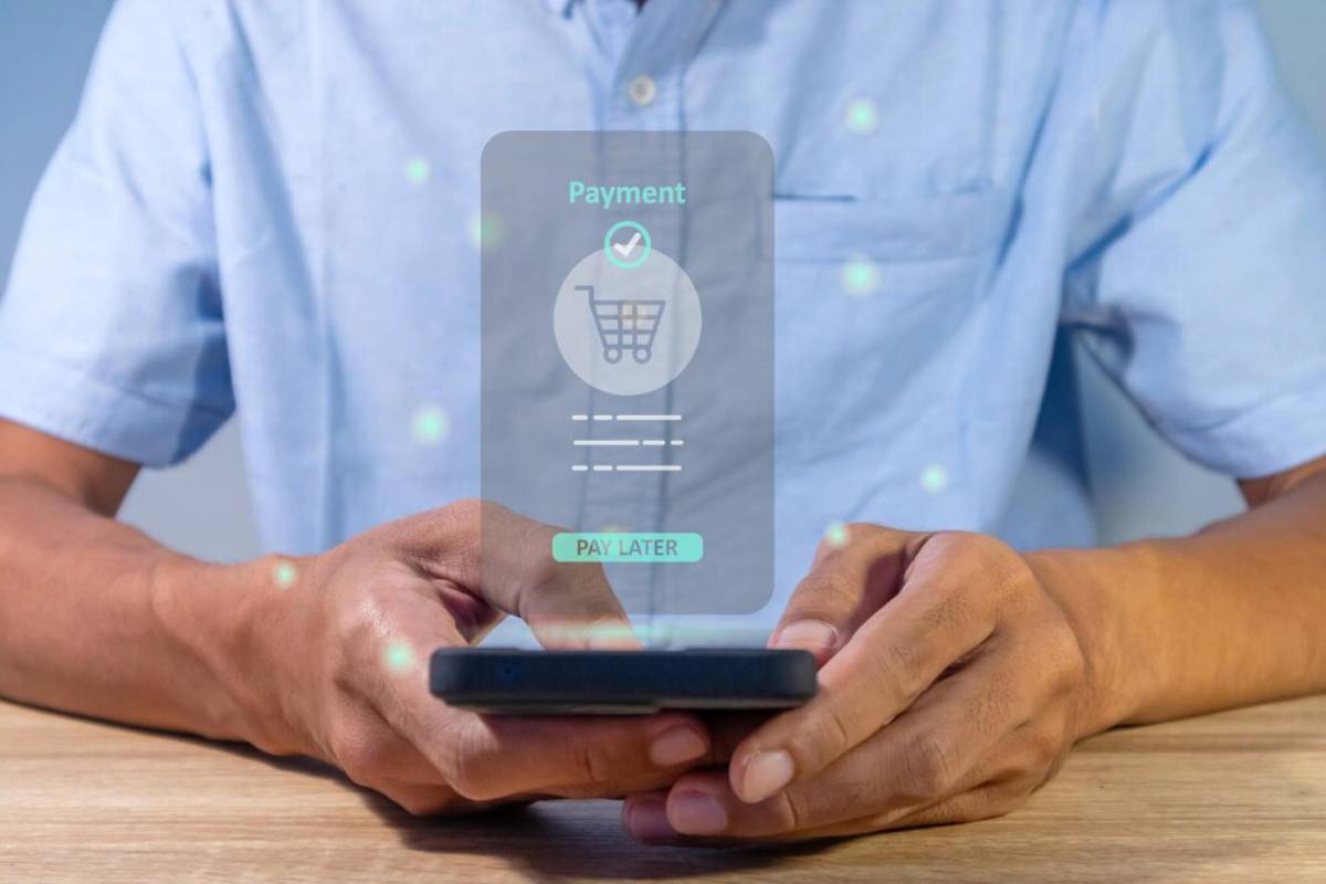 A person holds a smartphone displaying a digital payment interface with options to confirm and choose Pay Later.