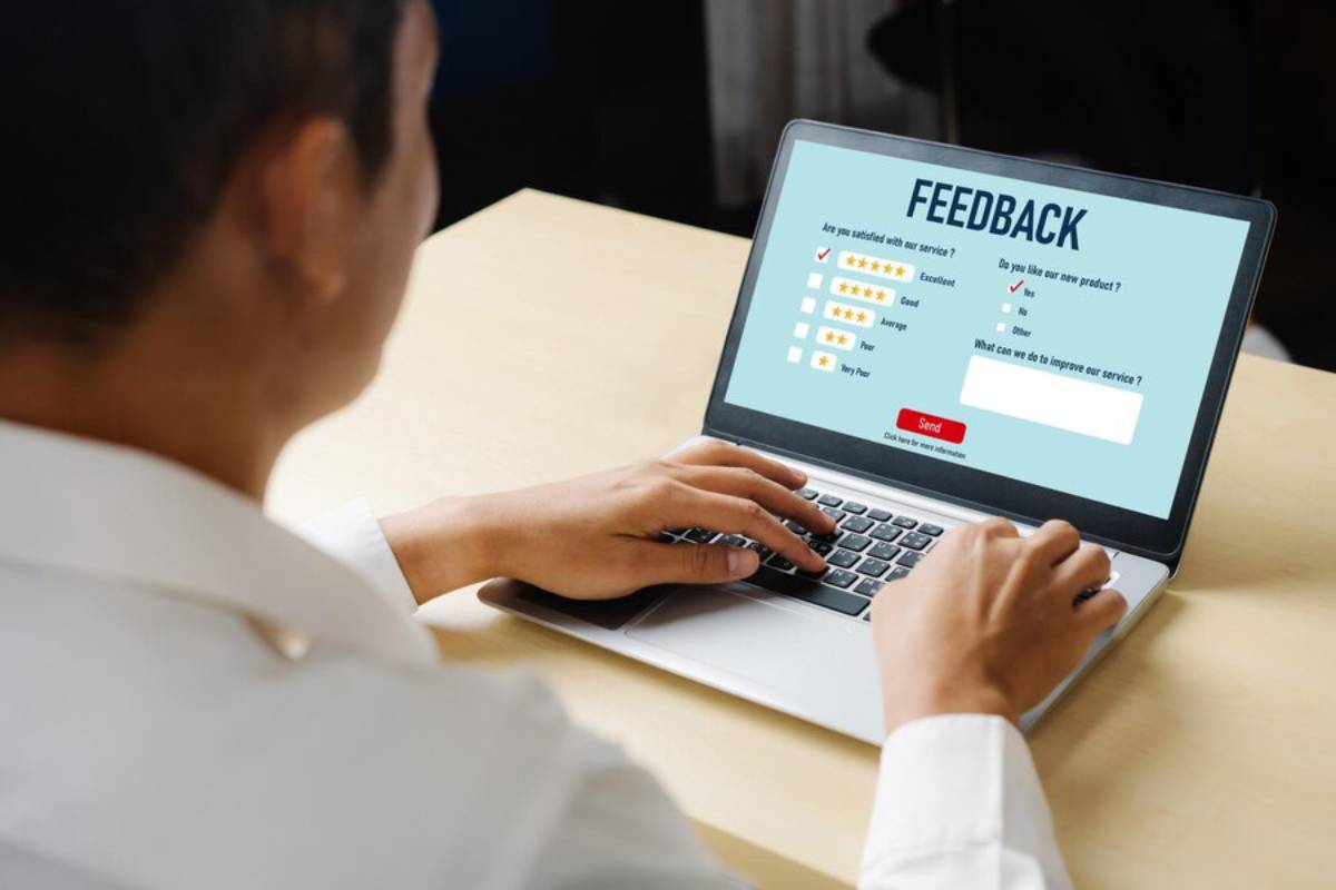 A person is filling out an online feedback form on a laptop, with rating options and a comment section visible.