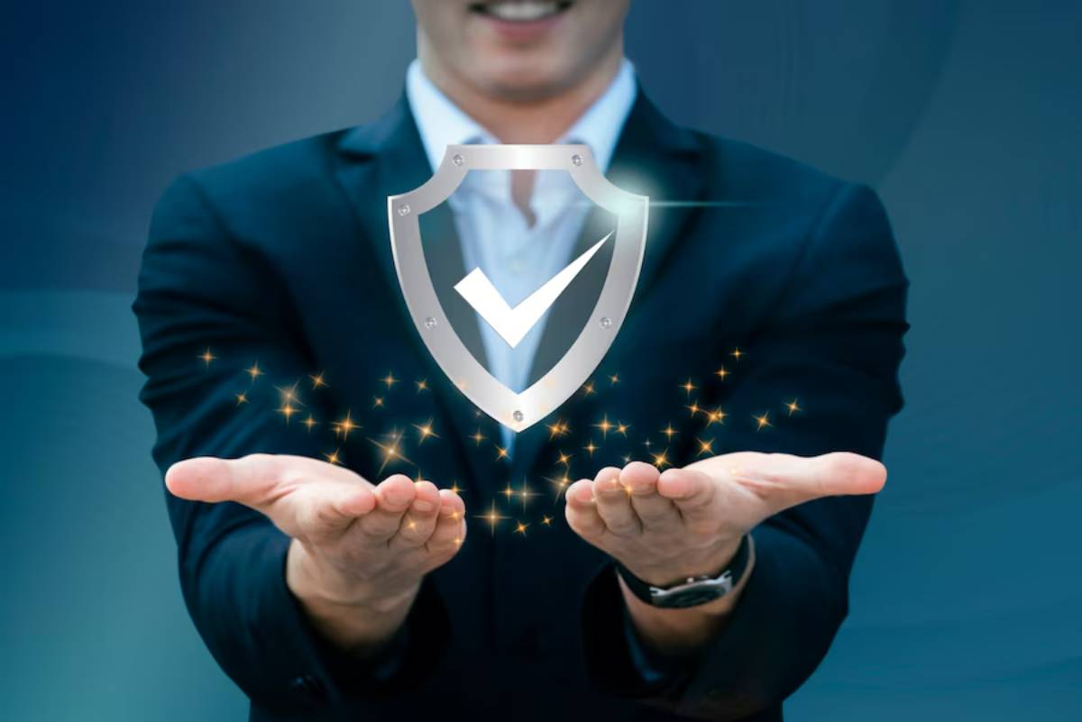A businessman in a suit holds out his hands, showcasing a glowing shield with a checkmark symbol, representing security and trust.