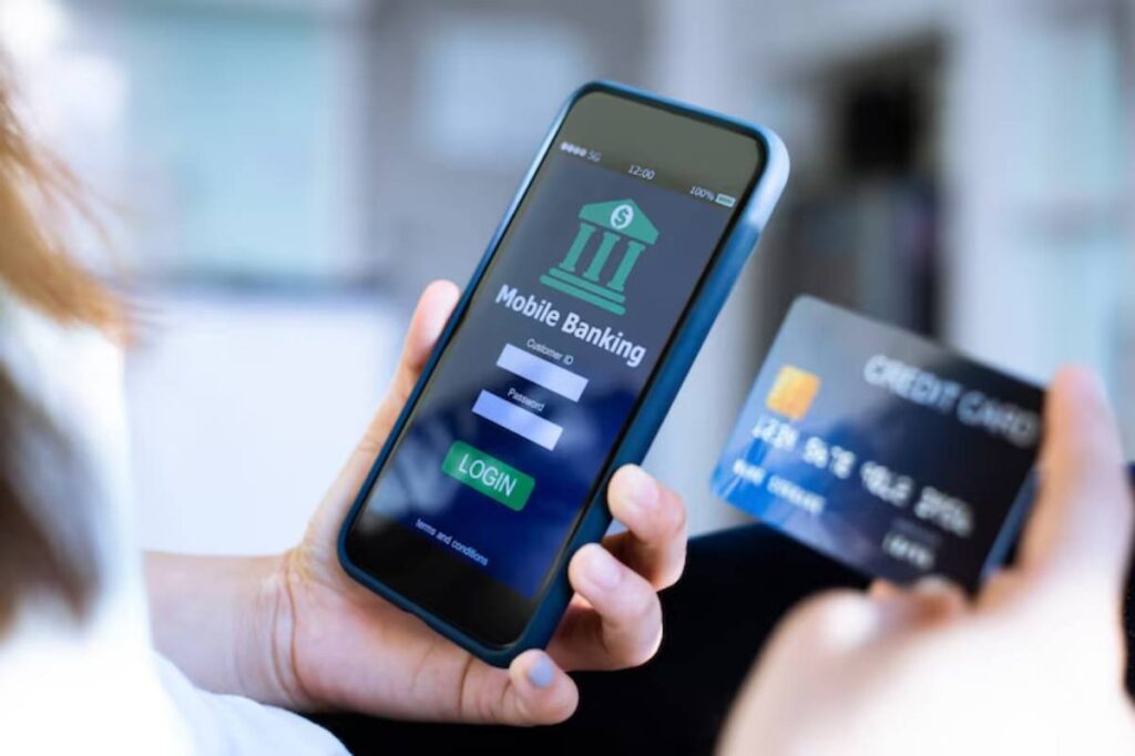 A person holding a smartphone displaying a mobile banking login screen, while using a credit card.