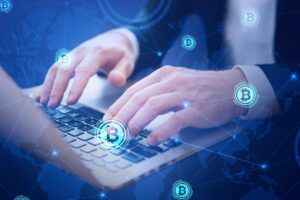A person typing on a laptop with a digital network overlay featuring Bitcoin symbols, symbolizing cryptocurrency trading or finance.