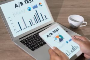A person holds a tablet displaying A/B Test graphs, while a laptop next to them shows more detailed A/B test analytics.