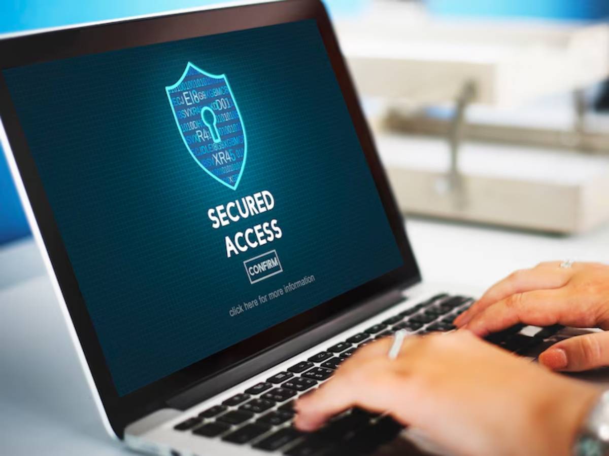 A person typing on a laptop displaying a Secured Access screen with a shield icon and a confirmation button.