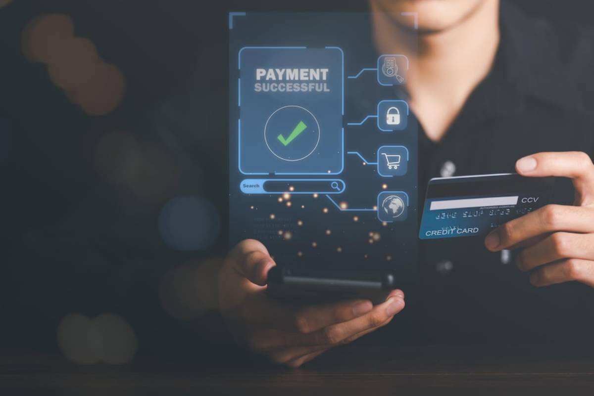 A person holding a smartphone displays a Payment Successful notification, while also holding a credit card in the other hand.